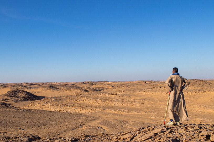 Человек стоит в пустыне, песок и жара